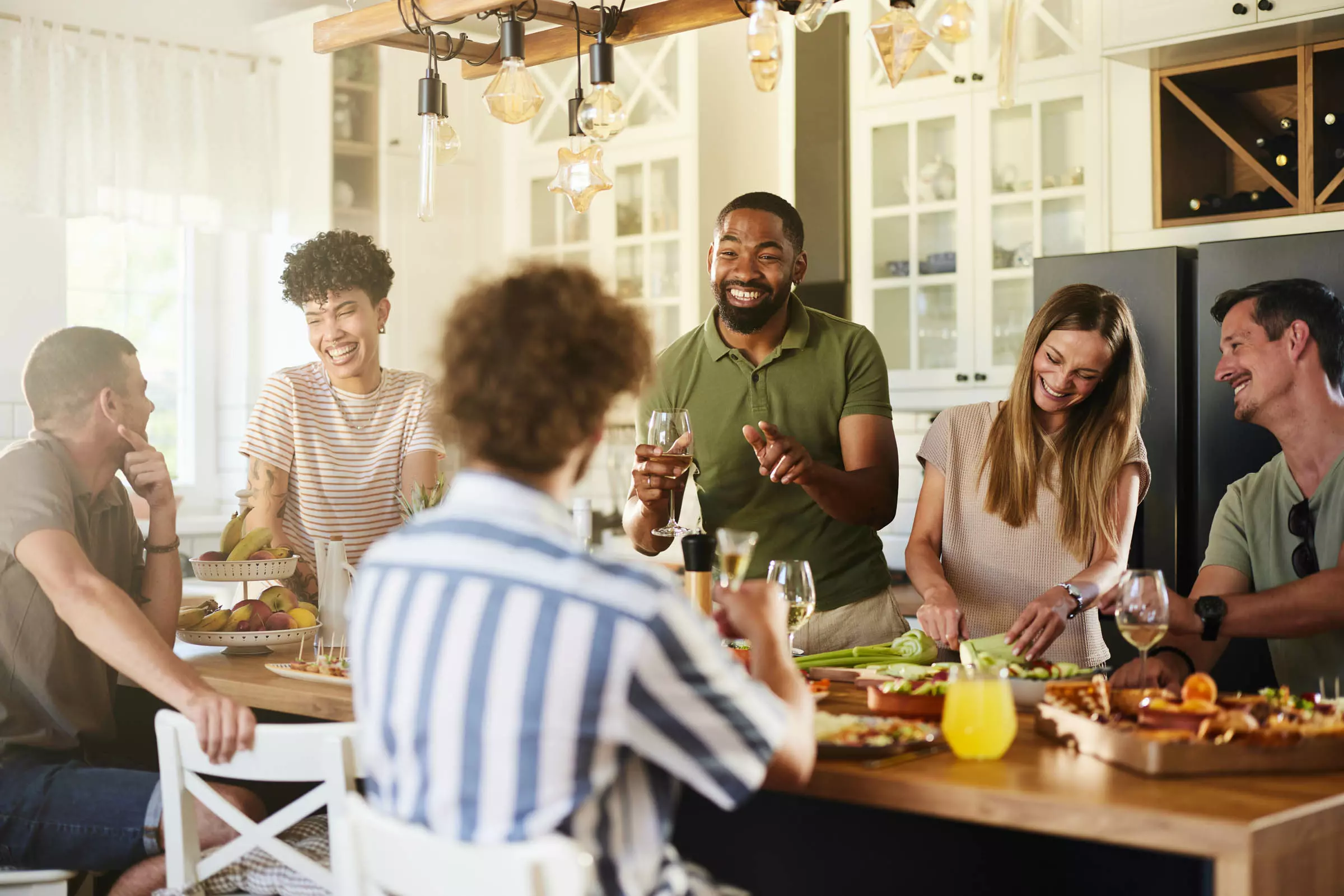 Diverse group of friends laughing and sharing a meal in a bright kitchen