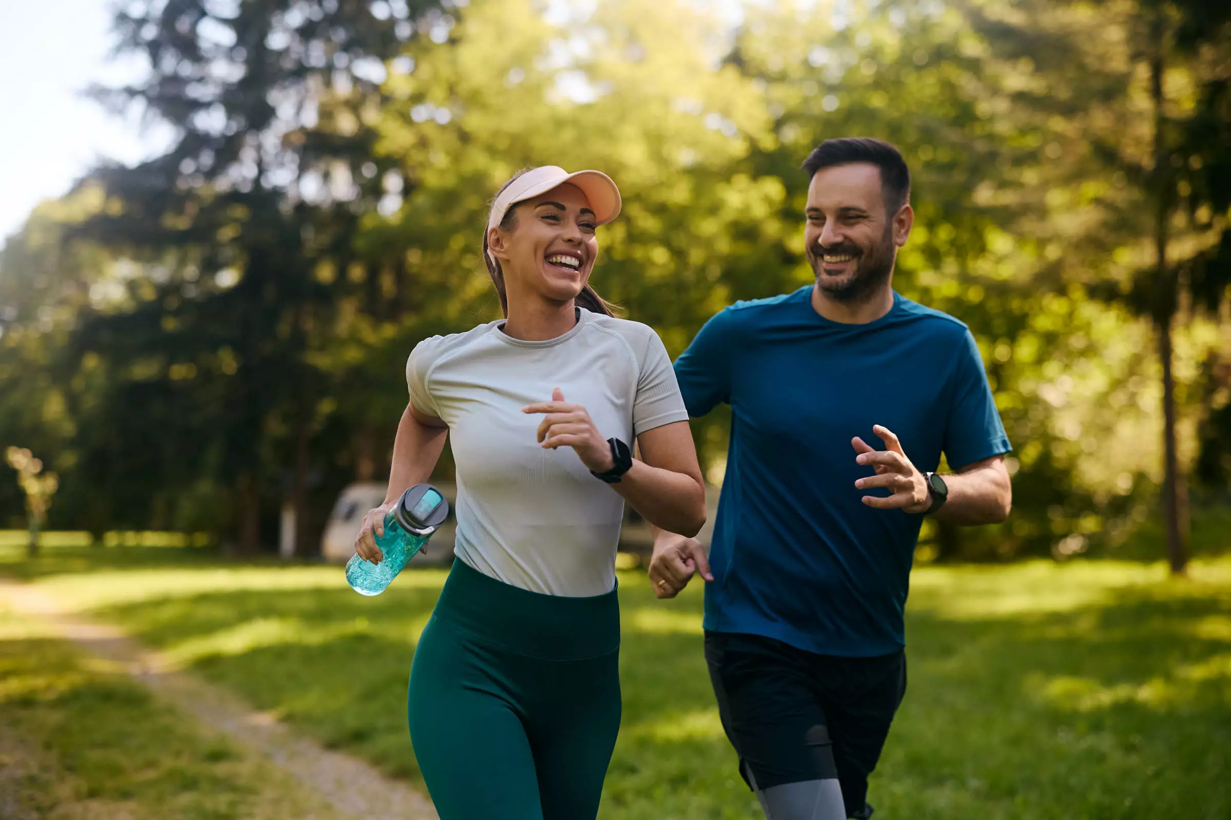 Smiling couple jogging together on a sunlit park trail