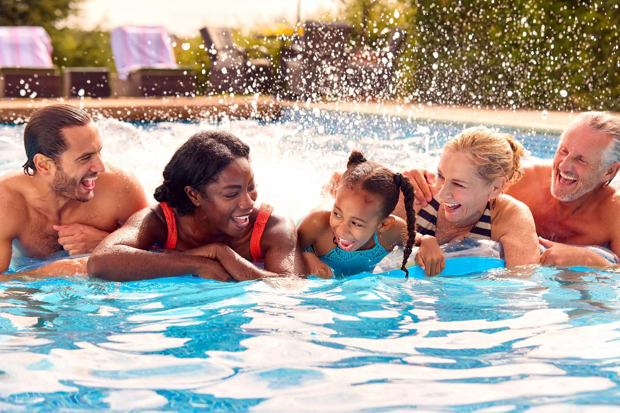 Multigenerational family laughing and playing together in a swimming pool